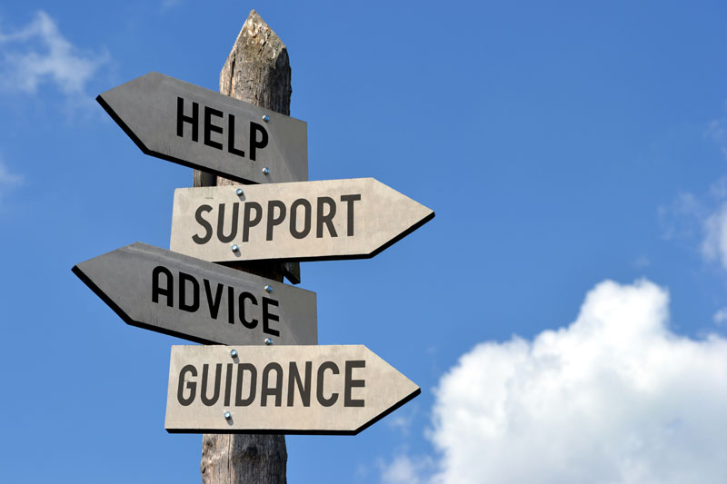 Wooden signpost with help, support, advice, guidance arrows against blue sky