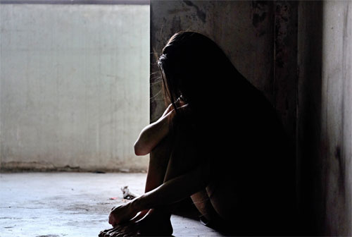 Girl sitting in corner of dark dirty room