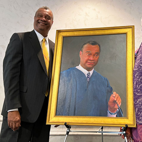 This is an image of a man standing next to a painted portrait of himself.