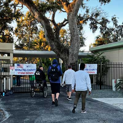This is an image of four men, one is sittning on a tricycle, walking through the entrance of a gate.